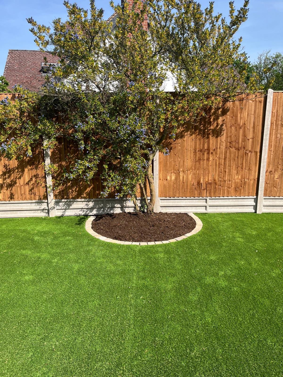 Landscaped garden with a circular block-edged tree bed, lawn and new close-board fencing